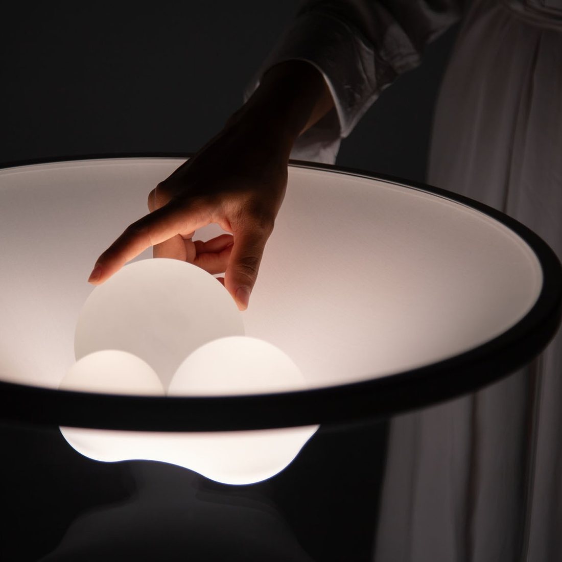 A hand resting a glass sphere into the lit crater